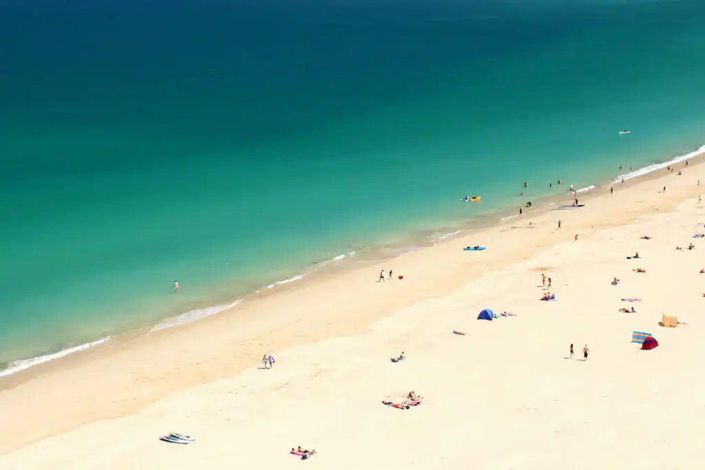 Aerial view of Carbis Bay Beach, featuring people enjoying the sandy shore and the calm blue waters.
