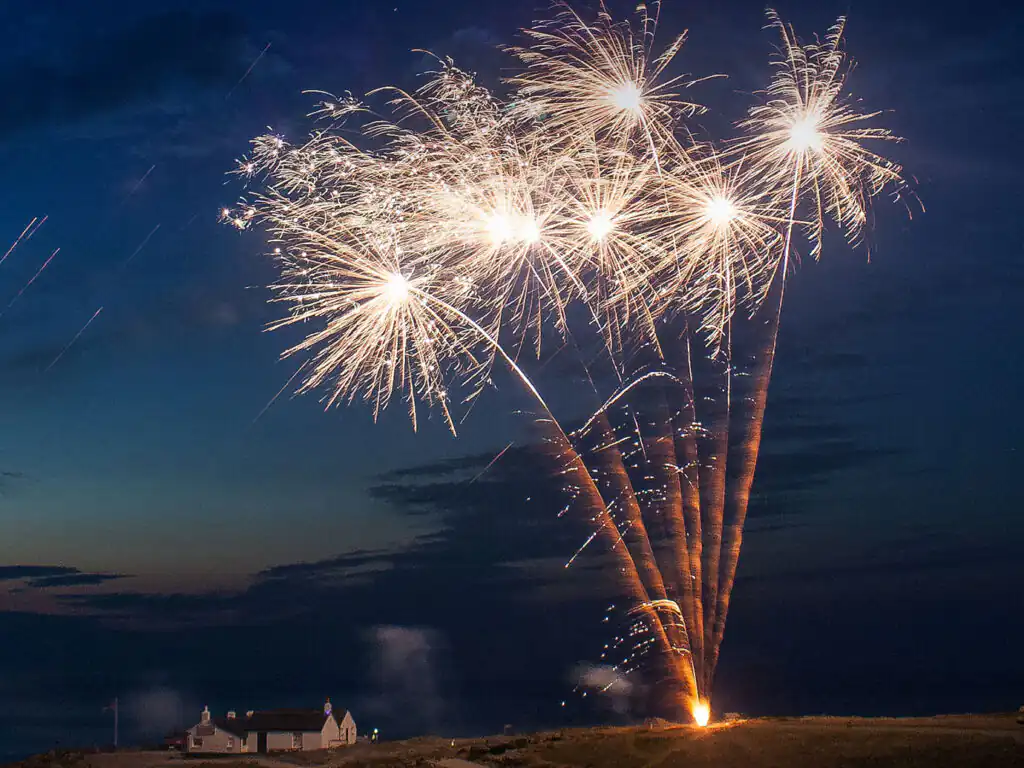 A vibrant firework bursts in the night sky during New Year celebrations at Lands End, Cornwall, experience this event from a new year holiday cottage in Cornwall.