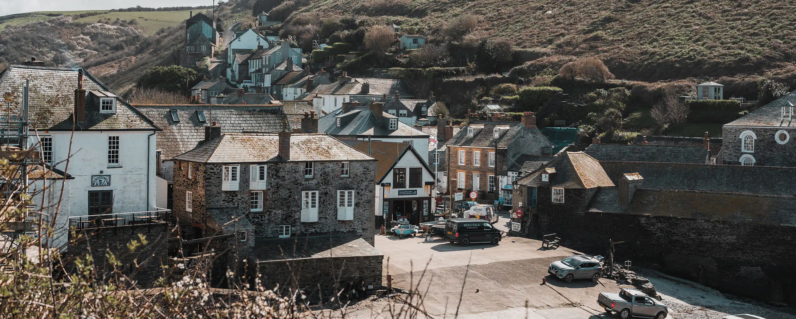 Scenic view of Port Isaac Harbour, featuring a coastal town with a hill rising in the background, just steps away from a Port Isaac Holiday Cottage.