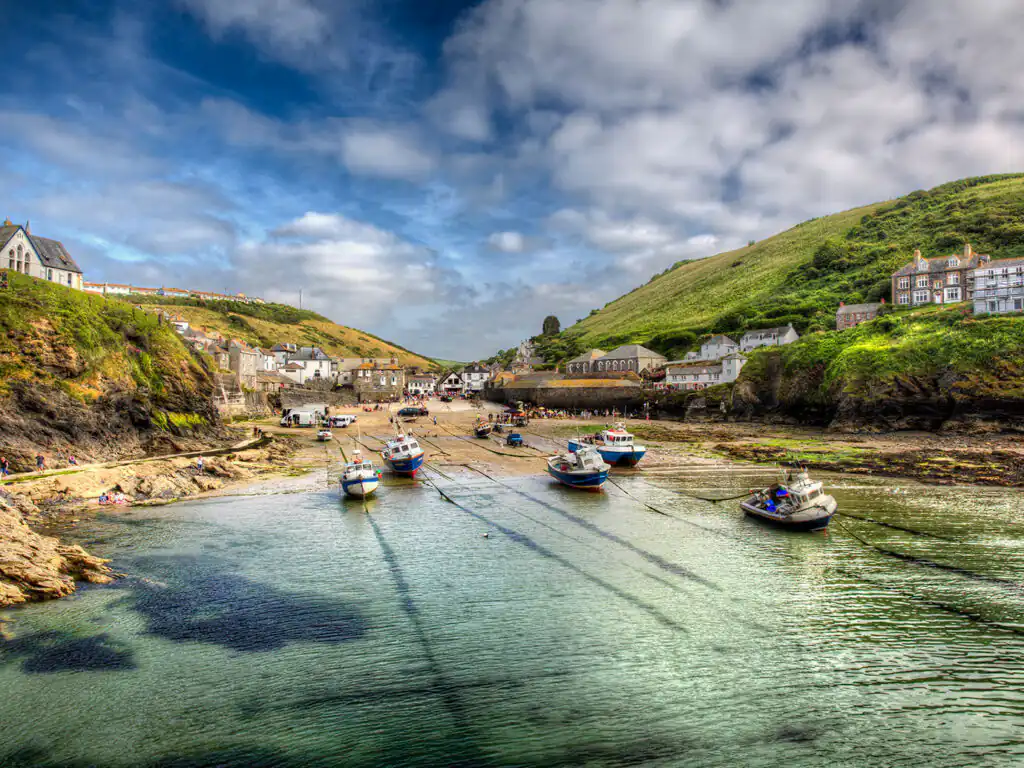 Vibrant view of Port Isaac's Harbour and beach, featuring a hill rising in the background, just steps away from a Port Isaac Holiday Cottage.