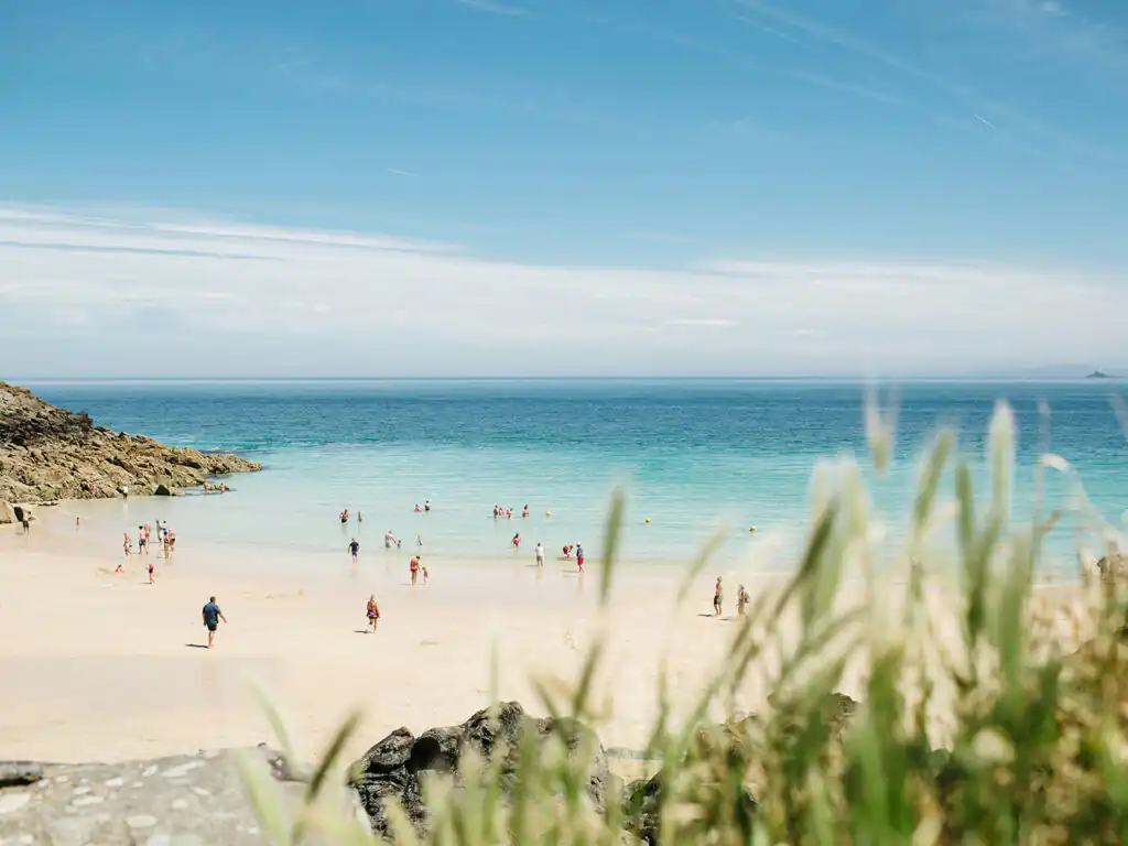 People relax and enjoy the sunny day at Porthgwidden Beach, St Ives, a great place to visit from your St Ives holiday cottage.