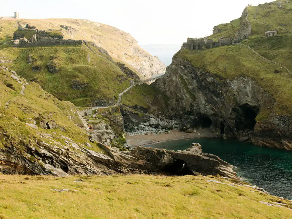 Grassy hillside overlooking the ruins of Tintagel Castle, part of Cornish arts and heritage.