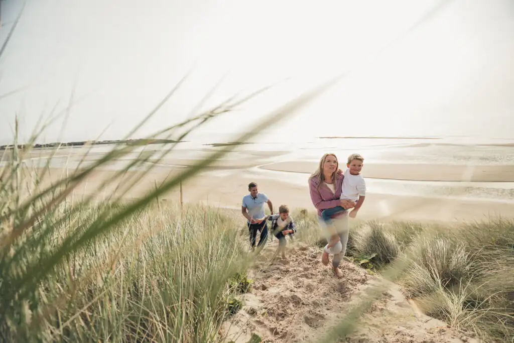 Family enjoying a sunny day walking along the beach in Cornwall during Easter 2026.
