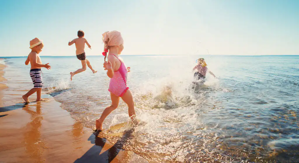 A group of children playing on a picturesque Cornish beach, laughing and enjoying the seaside.