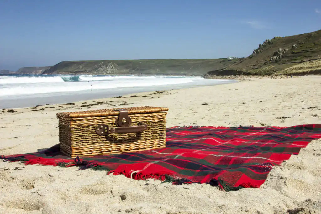 A colourful picnic blanket spread on the sandy beach, perfect for enjoying Easter food in Cornwall.