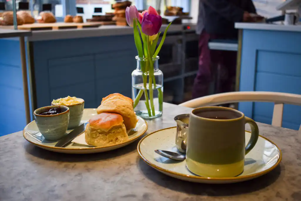 A table set with a cream tea and a vase of fresh flowers, inviting for a delightful experience in St Ives.