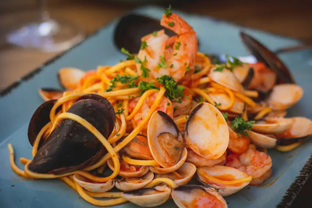 A plate of pasta topped with clams and shrimp, showcasing a delicious seafood dish perfect for a romantic meal in Cornwall.
