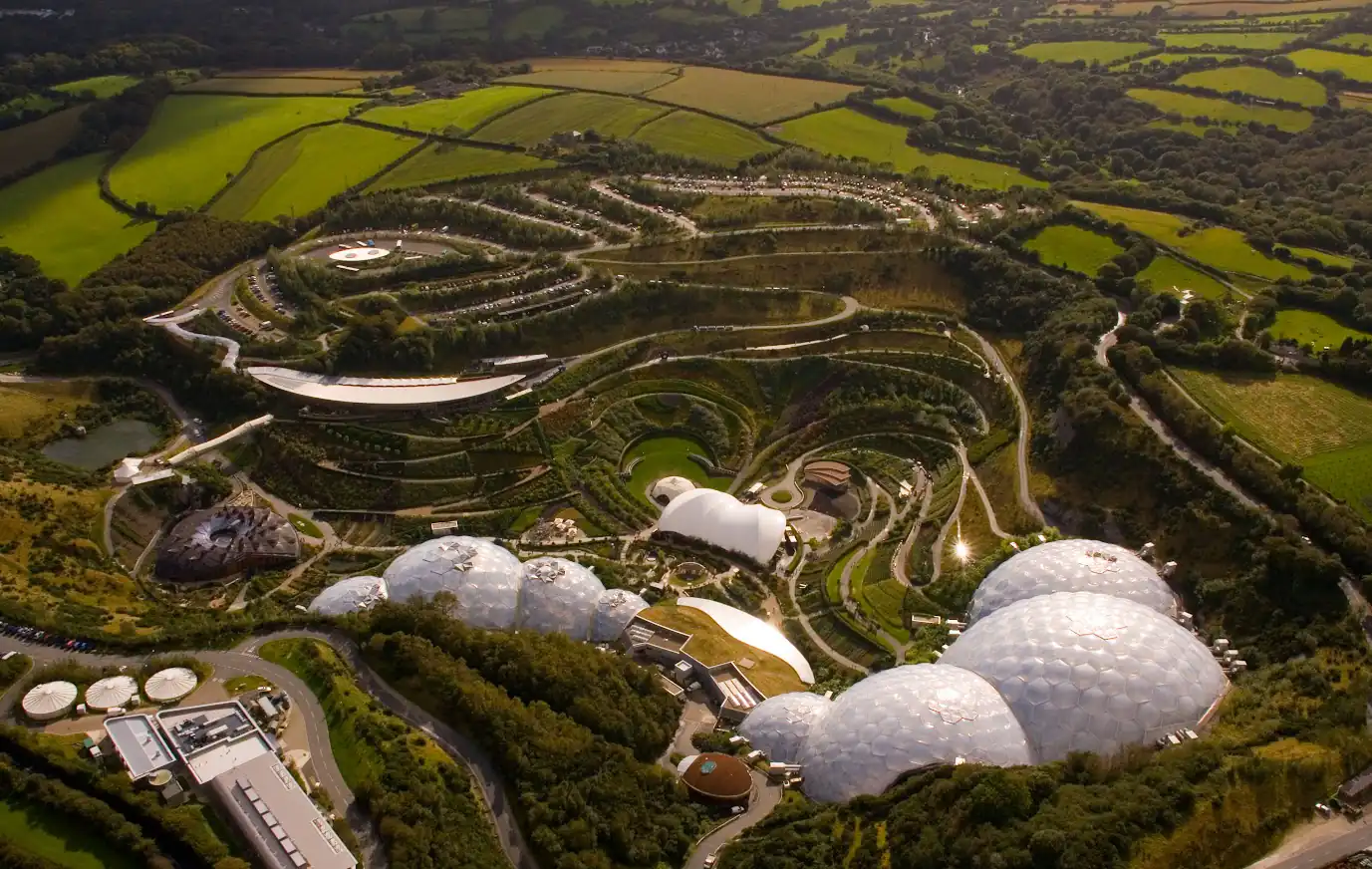 Aerial perspective of The Eden Project's expansive domes set amidst rolling green fields near St Austell.