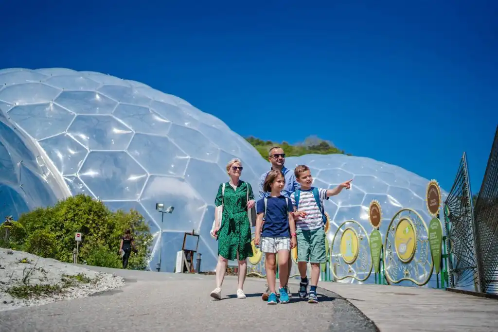 A family in front of the large biome domes at The Eden Project, showcasing their visit.