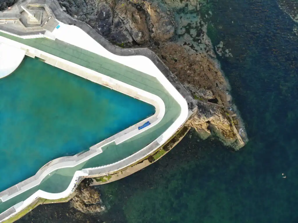 Overhead view of the Jubilee Pool nestled by the ocean, surrounded by the picturesque coastline of Penzance, perfect for wet weather.
