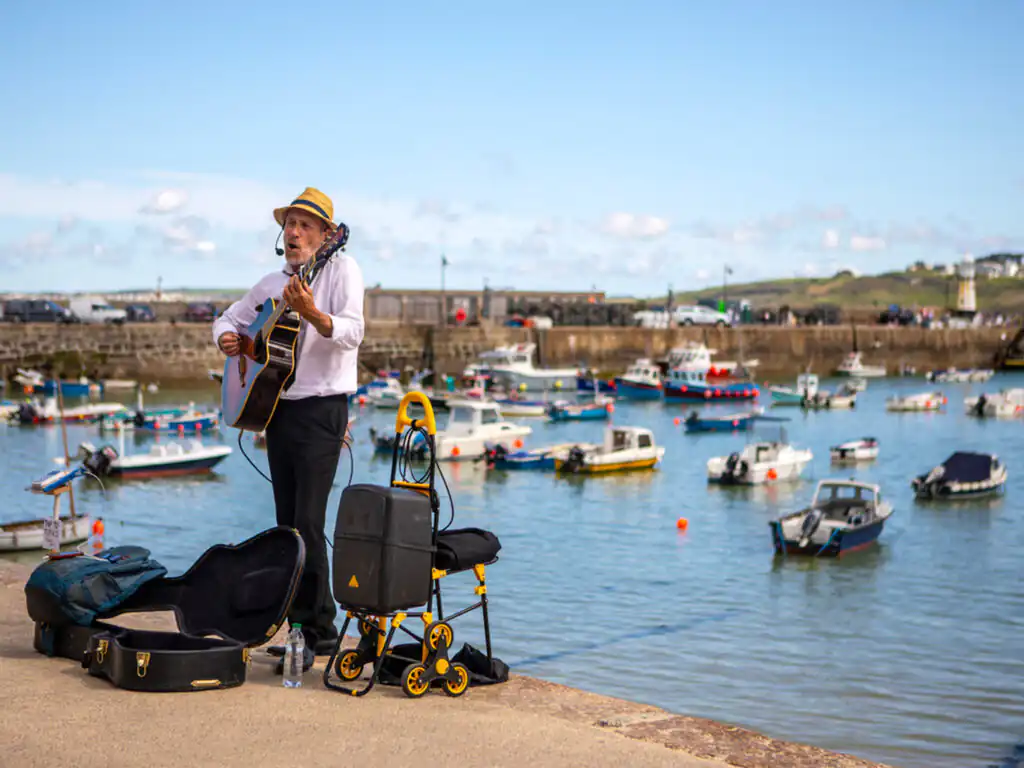A man playing guitar and singing at the St Ives September Festival, showcasing local talent and vibrant culture, a must see in St Ives.