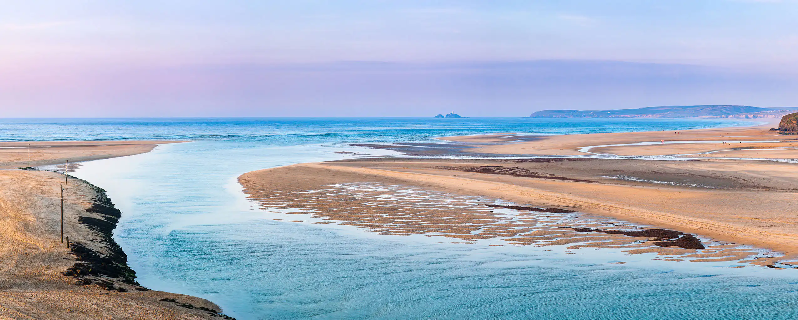 A serene Porthkidney Beach, merging with the sandy shore under a clear blue sky, great for a walk from a Cornwall cottage sleeping 2.