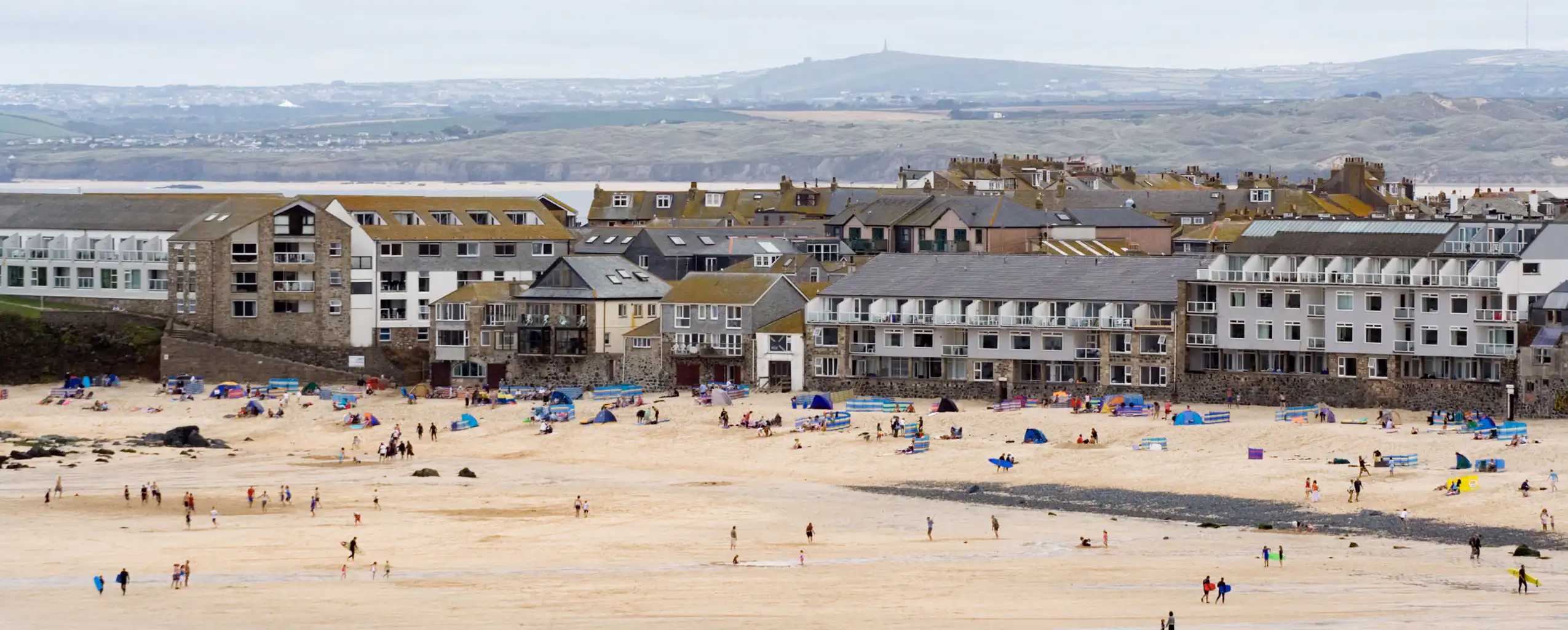 A picturesque Porthmeor Beach in front of a range of Cornwall Apartments, perfect for relaxation and seaside activities.