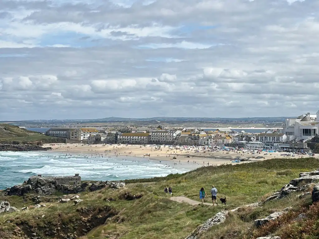 Scenic view of Porthmeor Beach with golden sands and hillside buildings in Cornwall.