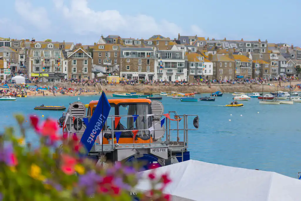 Bright blue sky with soft white clouds above St Ives Harbour, showcasing the RNLI lifeboat transport area.