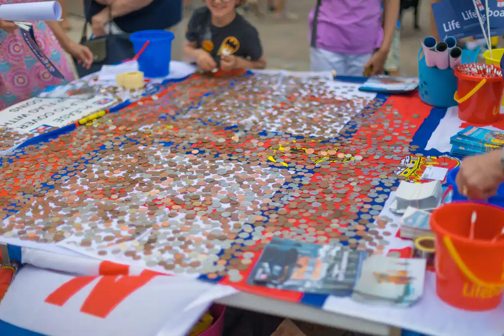 A table filled with various coins, part of kids' activities at the RNLI event in Cornwall.