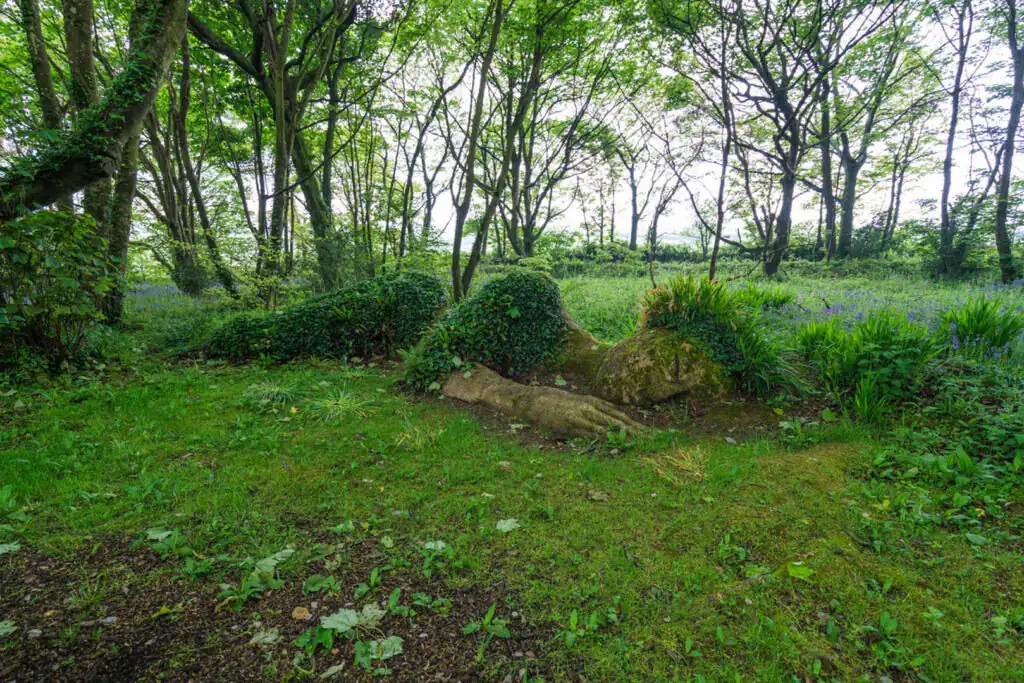 A striking sculpture is nestled in a vibrant forest, featured in The Lost Gardens of Heligan.