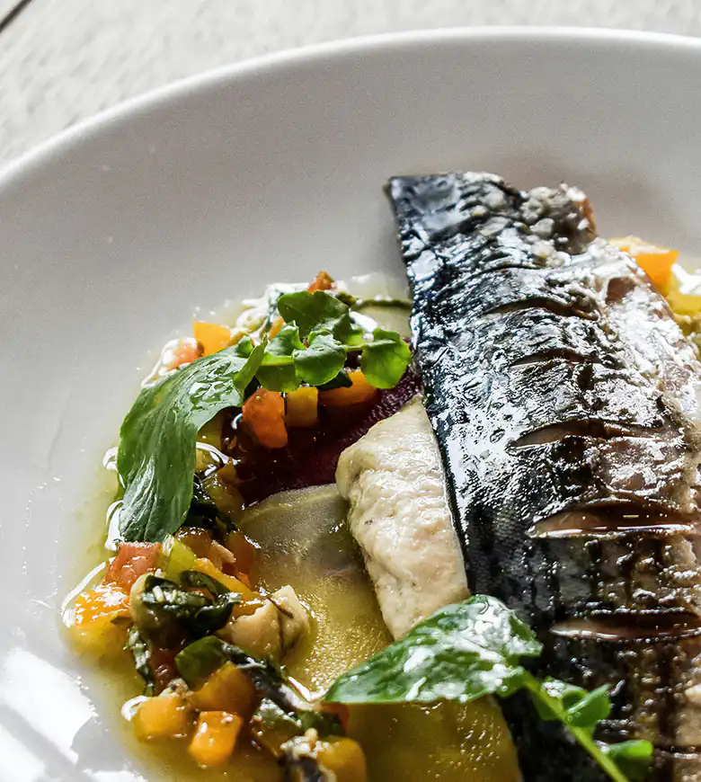 A plate of seafood featuring fish and colorful vegetables, showcasing the culinary delight of Carbis Bay in Cornwall.