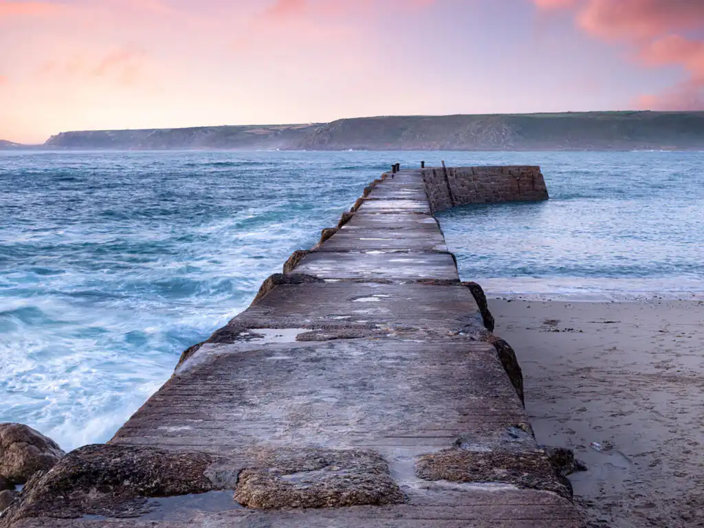 A picturesque view of Sennen Cove Harbour Wall in Cornwall, a top place to visit from a romantic holiday cottage in Cornwall.