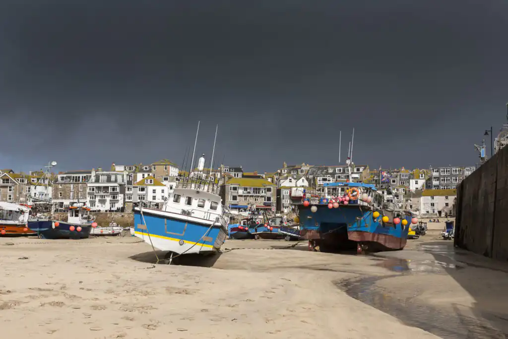 A moody sky darkens over St Ives Harbour, perfect for exploring indoor attractions on a rainy day.