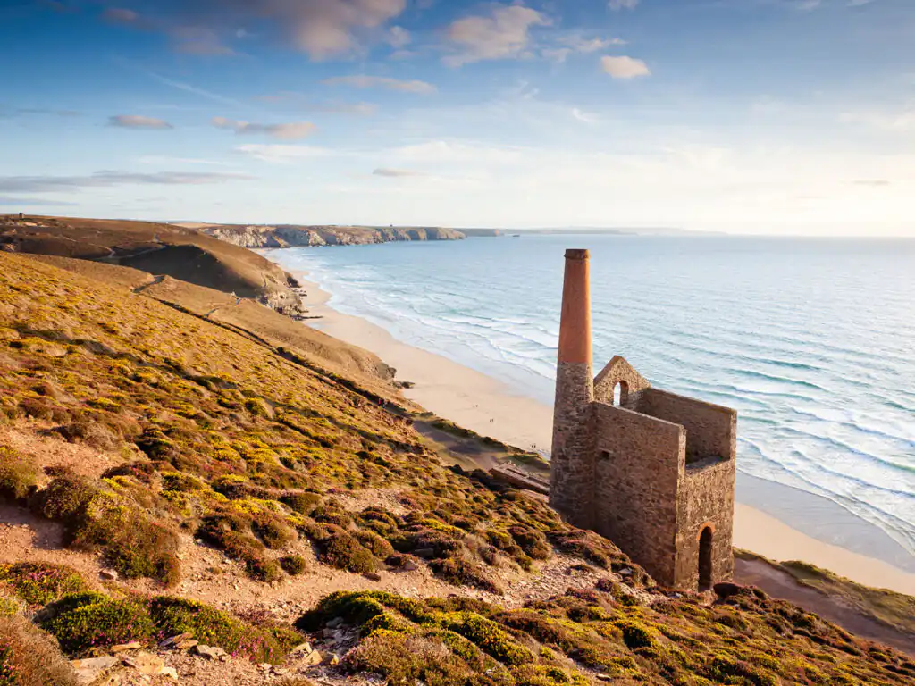 Scenic view of Towanroath Engine House on a hill overlooking a sandy beach and the ocean, near St Agnes, a popular holiday destination in Cornwall.