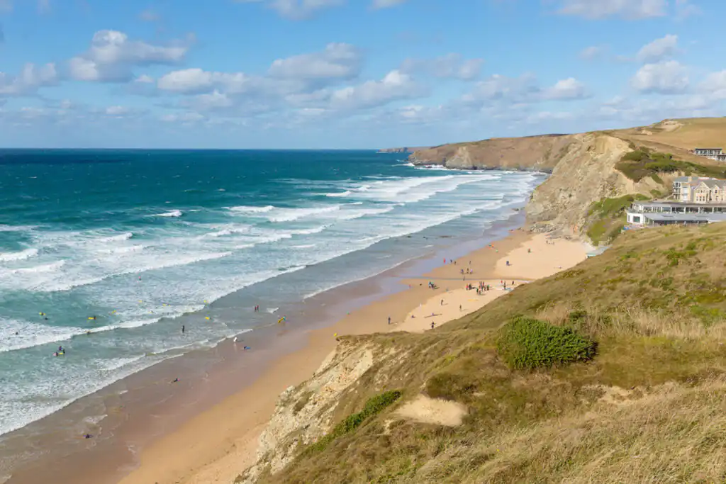 A sunny beach at Watergate Bay in Cornwall, with a few people enjoying the sand and surf, perfect for dogs.