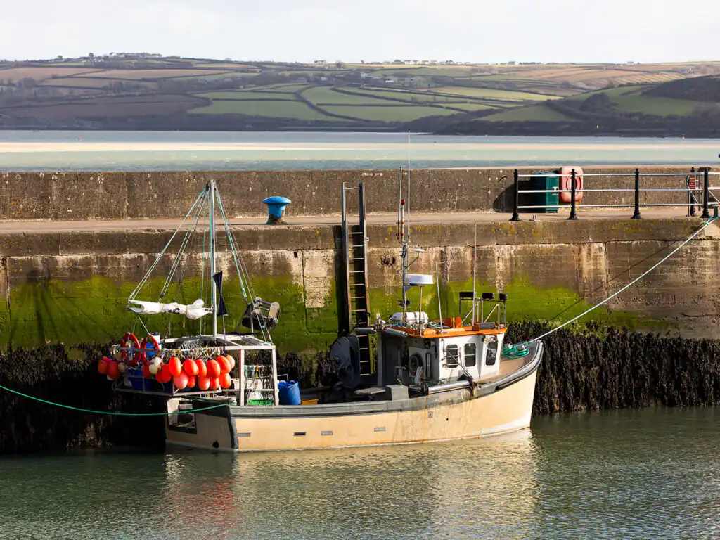 A boat securely moored at a dock in Padstow Harbour, surrounded by calm waters and scenic views.