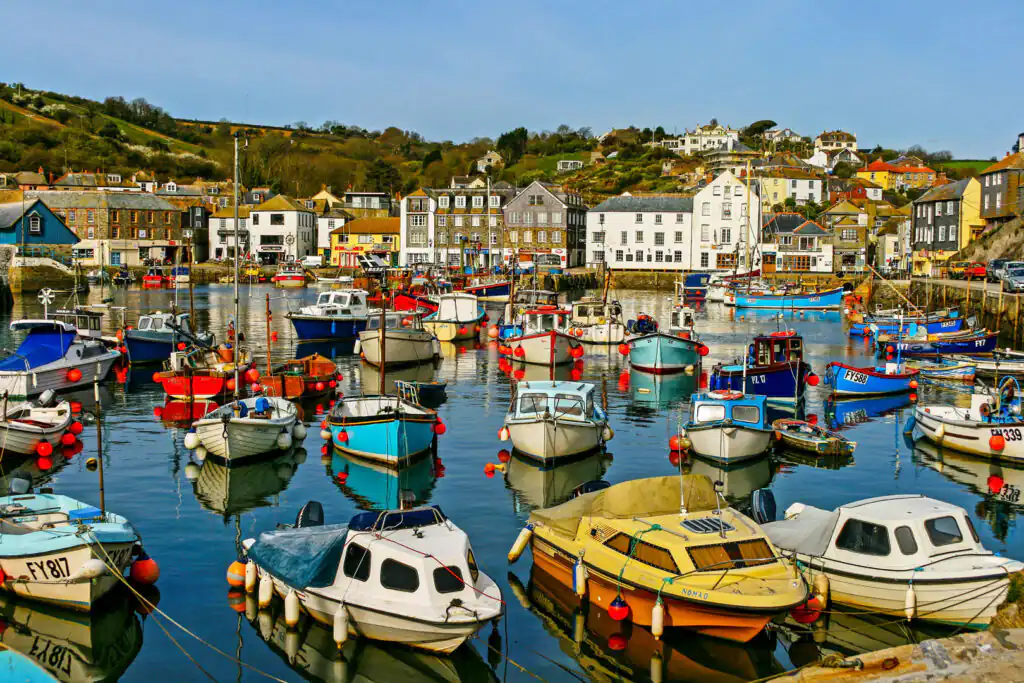 A bright blue sky dotted with fluffy white clouds over Mevagissey, highlighting the beauty of Cornwall’s fishing villages.