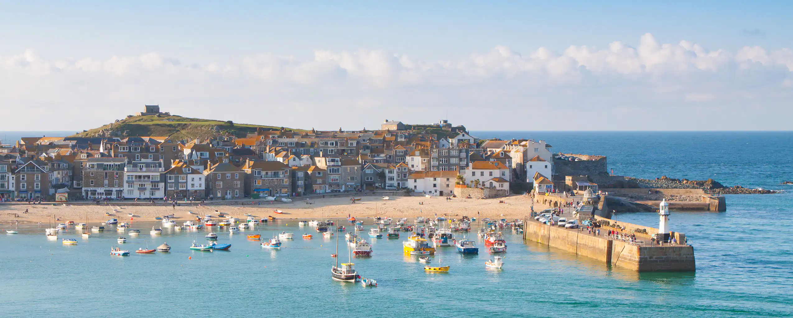 Scenic view of St Ives Harbour in Cornwall, showcasing boats and the picturesque coastal landscape.