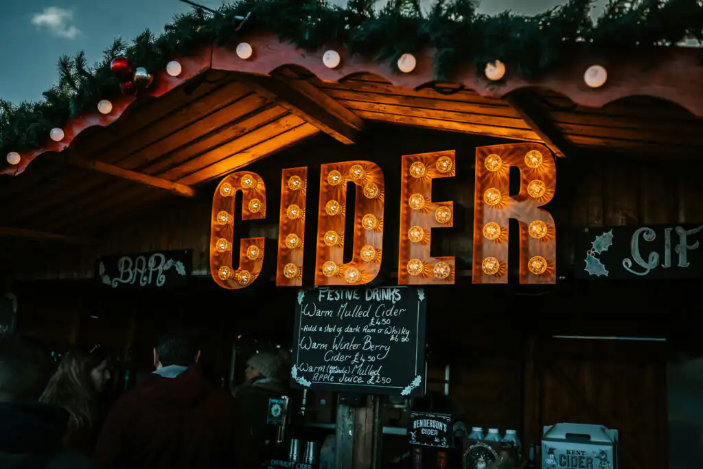 A vibrant sign that says "Cider" at the Penryn Jubilee Wharf Christmas Fair, showcasing a popular drink option for visitors.