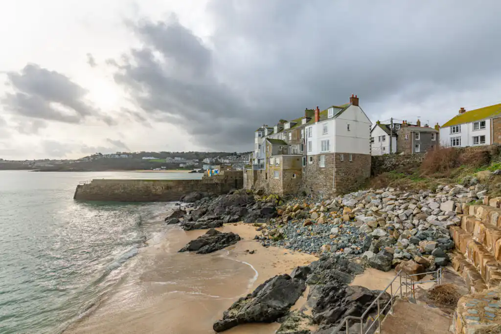 Scenic view of Bamaluz Beach in St Ives, with sandy shore and charming houses lining the coast, perfect for dog lovers.
