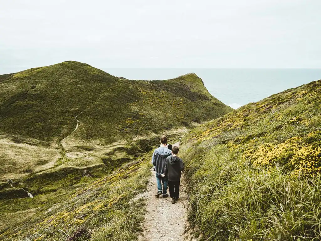 A family strolls on a scenic path near the ocean in Morwenstow, Cornwall, enjoying their holiday together.