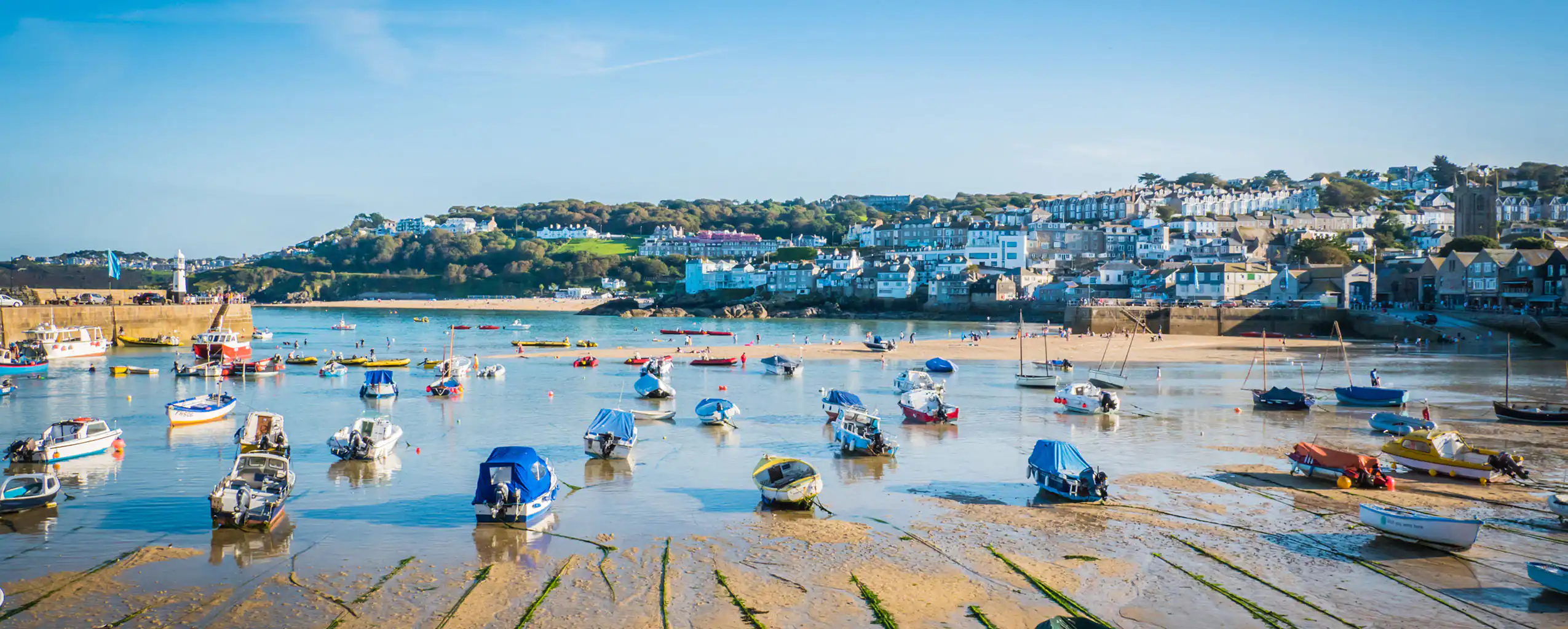 St Ives Harbour features boats moored in the water, surrounded by the picturesque town, don't hesitate to contact us to book a cottage with this view!