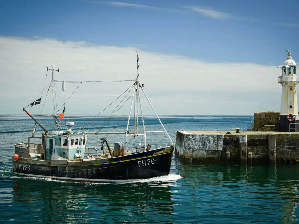 A boat approaches Mevagissey Harbour, reflecting the serene beauty of Cornwall's coastal weekend getaways.