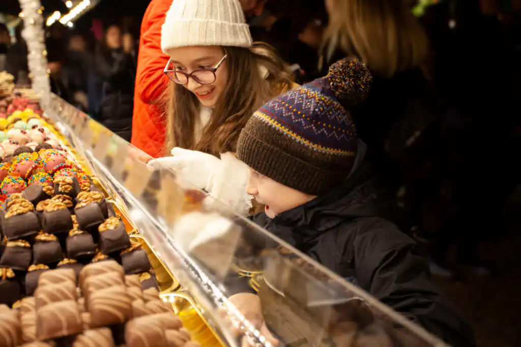 A woman and a child admire a colourful display of chocolates at the Looe Christmas Market in Cornwall.