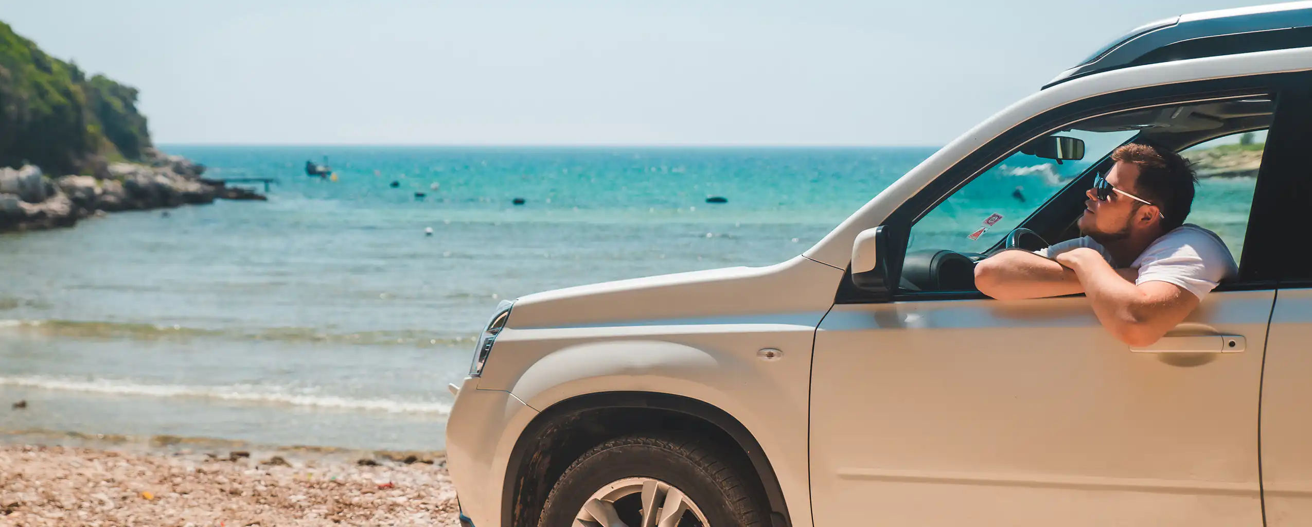 A man relaxes in the back of a car parked on the beach visiting from his Hayle Cottage with Parking, enjoying the seaside view.