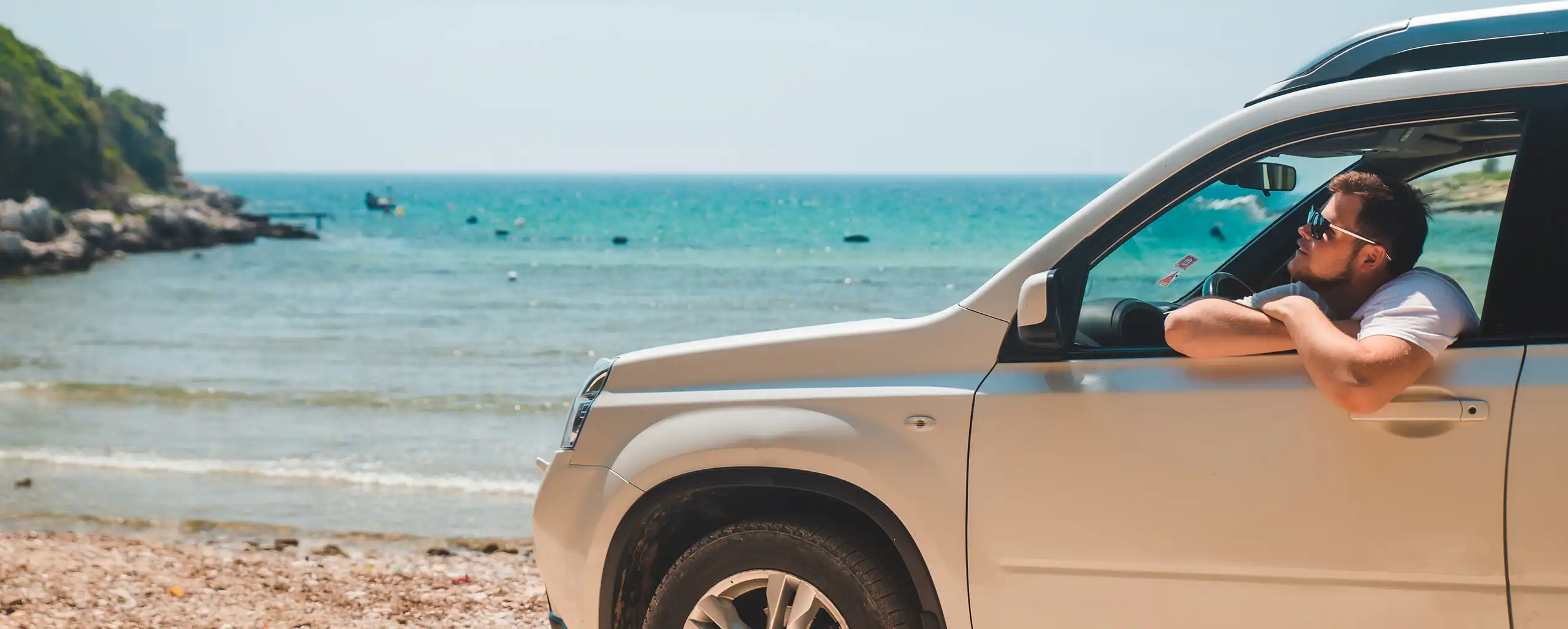 A man relaxes in the back of a car parked on the beach visiting from his Cornwall Cottage with Parking, enjoying the seaside view.