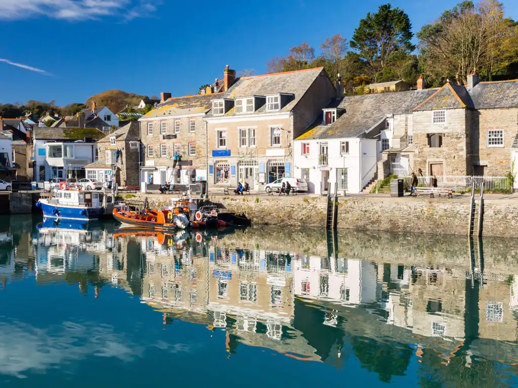A clear blue sky dotted with fluffy white clouds over Padstow Harbour, creating a serene coastal atmosphere.