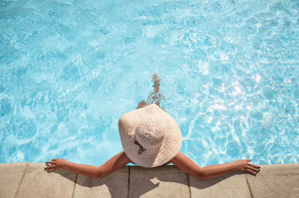 A woman in a hat relaxes in a serene sea pool, enjoying the tranquil atmosphere of West Cornwall.