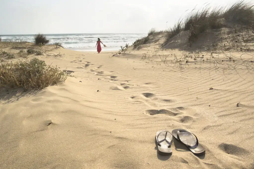 A woman relaxing amongst sand dunes in West Cornwall.