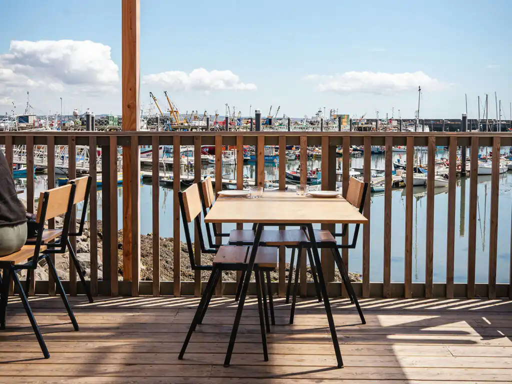A cosy wooden deck of a café, overlooking the picturesque Newlyn Harbour, a great place for food in Mounts Bay.