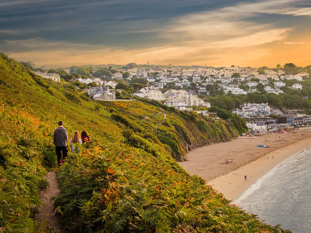 A couple strolls along the Carbis Bay coastal path, enjoying the scenic view of the beach nearby, a great walk to take from Lelant.