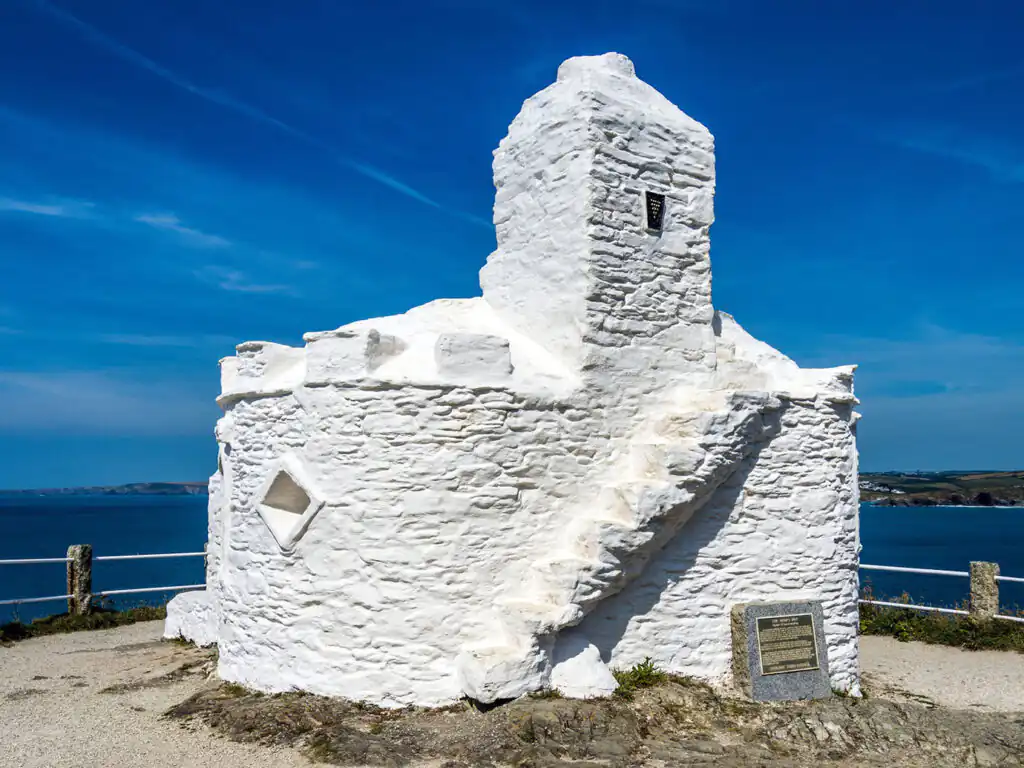 White stone Huer's Hut in Newquay, featuring a ladder on the roof against a clear blue sky, a part of Newquay's Heritage.