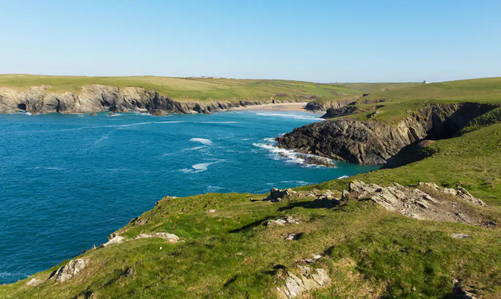 Rugged cliffs and blue ocean at Polly Joke Beach, Cornwall, with grassy cliff tops, a great hidden beach in Cornwall.