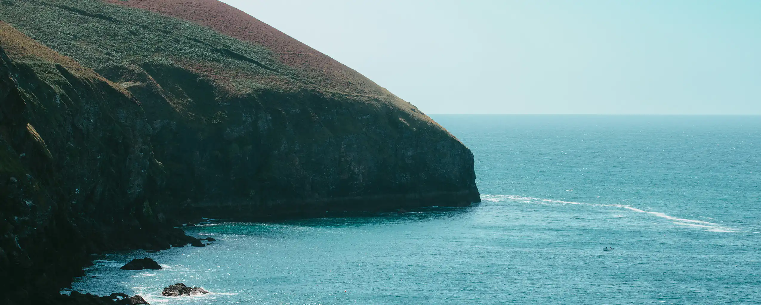 A vast body of water with coastal cliffs in St Agnes, showcasing the beauty of nature's rugged shoreline.