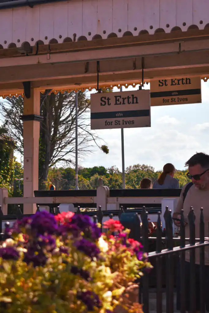 A man stands in front of St Erth Station, a picturesque train station near St Ives, the starting point of the most scenic rail journey in Cornwall.