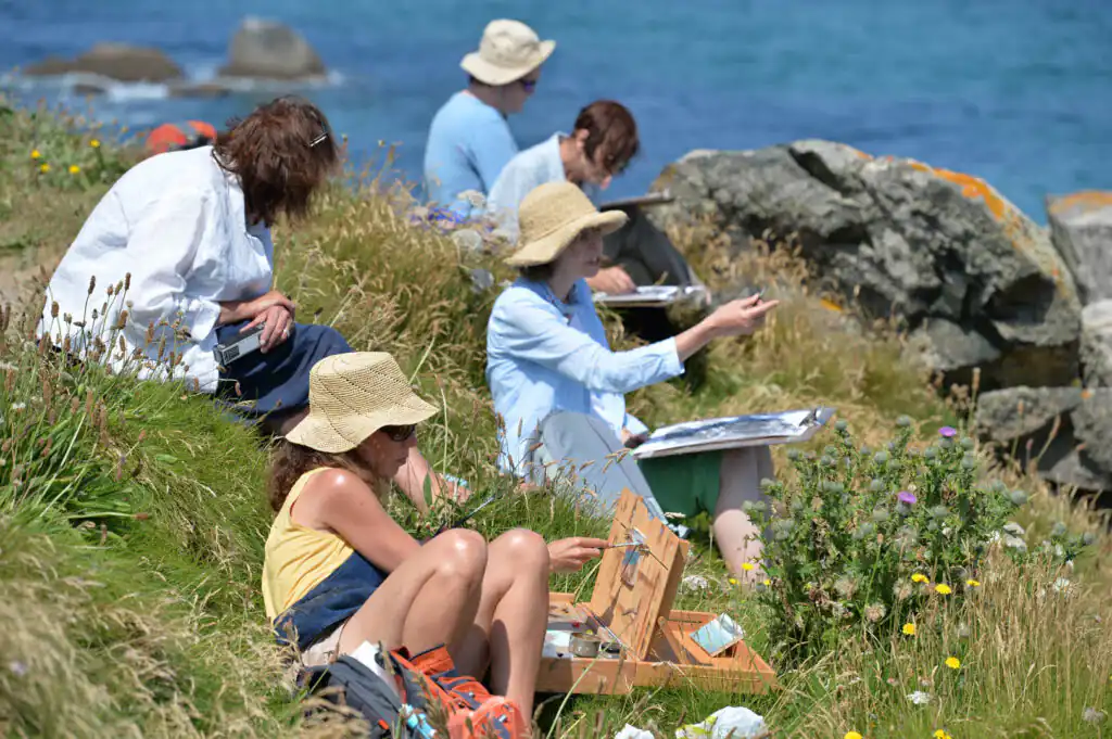 Artists from the St Ives School of Painting create artwork on cliffs along a coastal path in Cornwall.