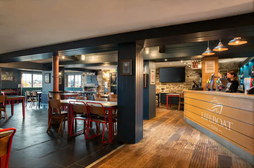 Inside The Lifeboat Inn, one of the best bars in St Ives, with a polished counter and several tables, perfect for socializing in St Ives.