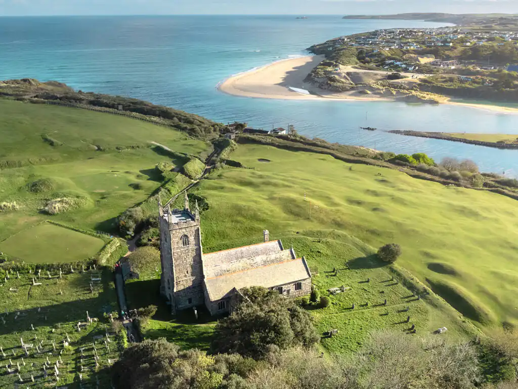 Aerial view of St Uny Church and the beach in Lelant, showcasing the scenic coastline and nearby West Cornwall Golf Club, a great thing to do in Carbis Bay.