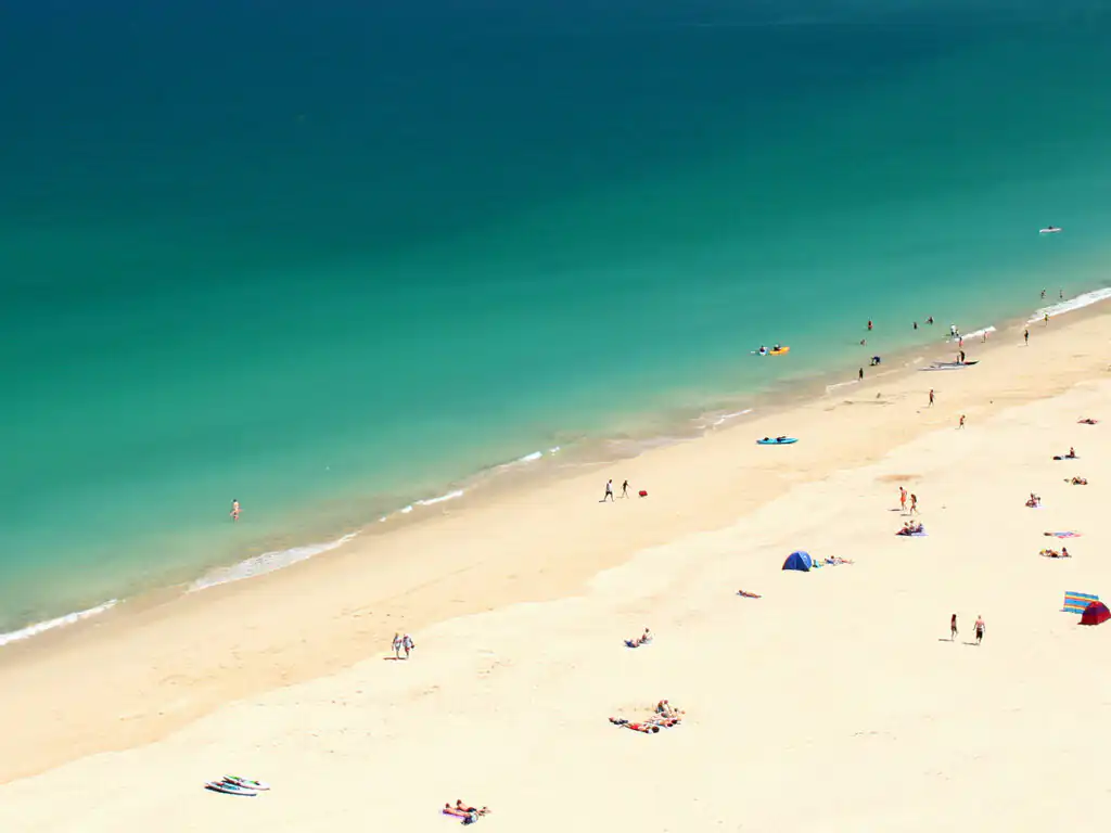 Aerial view of Carbis Bay Beach, featuring people enjoying the sandy shore and a vibrant blue ocean.
